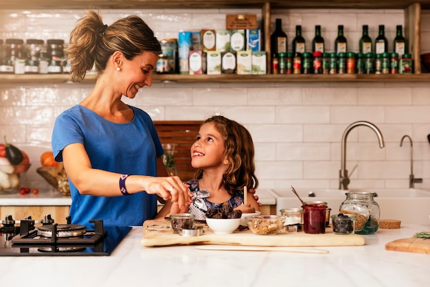 Menina cozinhando com a mãe na cozinha. Conceito de chef infantil.