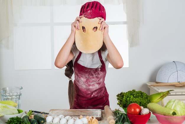 Menina cozinhando na cozinha, chef de cozinha, fazendo massa engraçada, preparando comida saudável em casa e vestindo uniforme de cozinheiro, arrumando e ajudando no desenvolvimento da infância