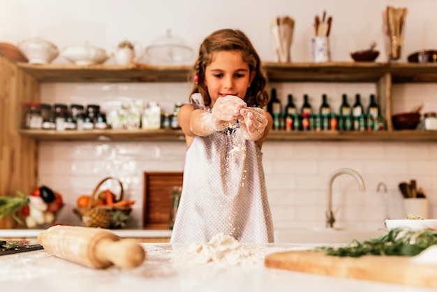 Menina criança amassando a massa, prepare-se para assar biscoitos. Conceito de chef infantil.