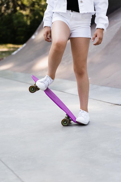 Menina criança andando na prancha de um centavo close-up Equipamento esportivo para crianças Adolescente com prancha de centavo no parque de skate