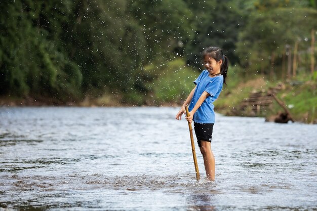 Menina criança asiática feliz brincando no rio se divertindo e curtindo com a natureza