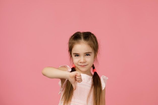 Menina criança bonita mostrando o gesto de polegar para baixo