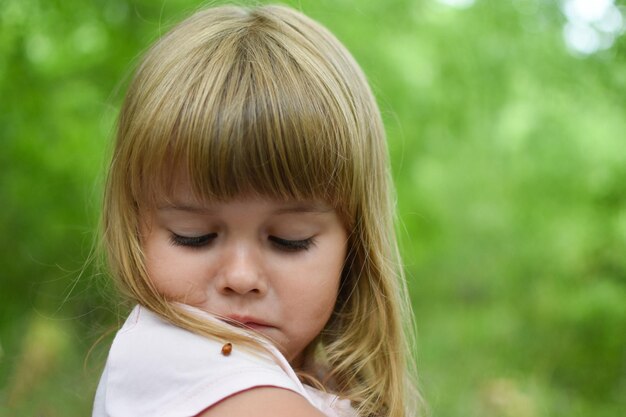 Menina criança brincando com uma joaninha ao ar livre