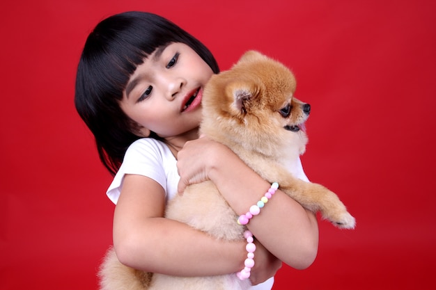 menina criança carregando um cachorro no estúdio.