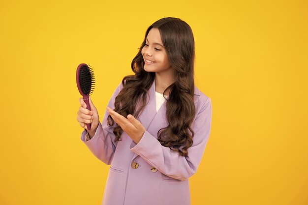 Menina criança com escova penteando o cabelo Menina cuidando do cabelo e penteado Rosto feliz emoções positivas e sorridentes da adolescente