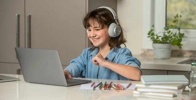 menina criança com fone de ouvido sorrindo e usando laptop em casa