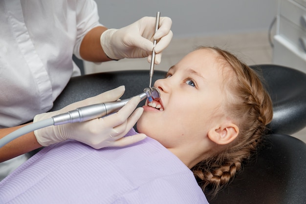 Menina criança com limpeza dentária profissional no consultório do dentista