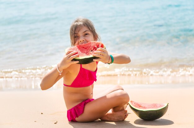 Menina criança comendo melancia à beira-mar