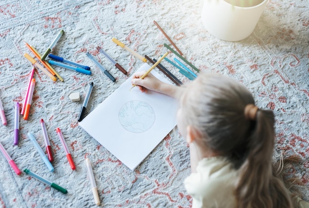 Menina criança desenhando com lápis coloridos