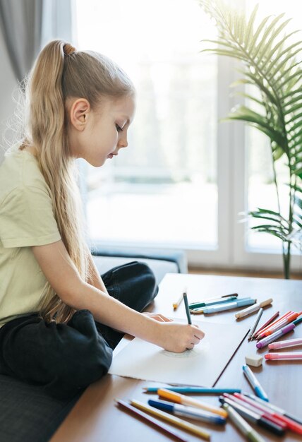 Menina criança desenhando com lápis coloridos