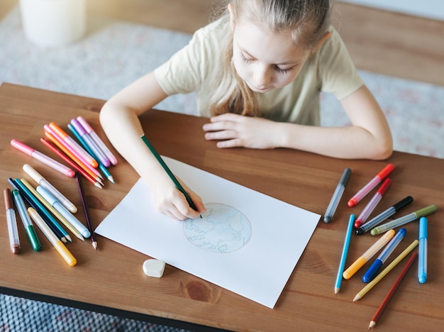 Menina criança desenhando com lápis coloridos