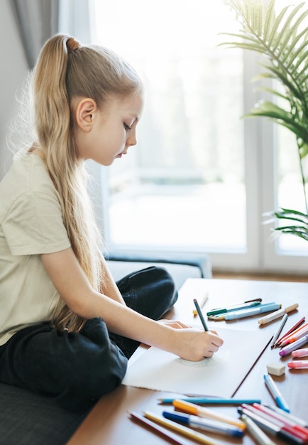 Menina criança desenhando com lápis coloridos