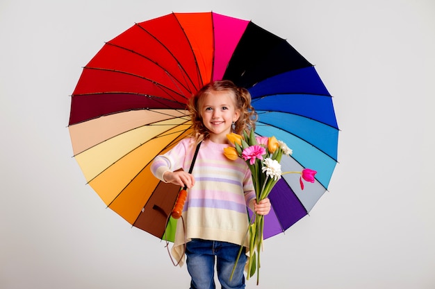 Menina criança em botas de borracha, segurando um guarda-chuva multicolorido