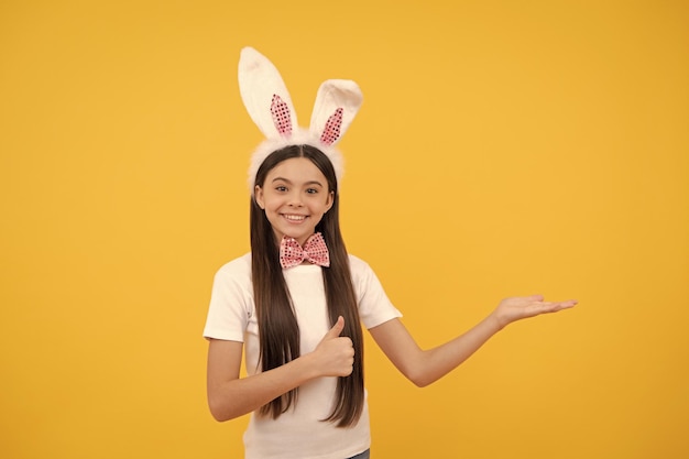 Menina criança em orelhas de coelho e gravata borboleta apresentando produto ou espaço de cópia de vendas de compras feliz páscoa