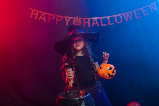 Foto menina criança engraçada fantasiada de bruxa para o dia das bruxas com jack de abóbora