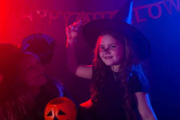 Menina criança engraçada fantasiada de bruxa para o Halloween com aranha.