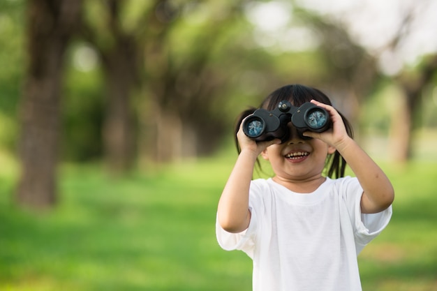 Menina criança feliz brincando com binóculos