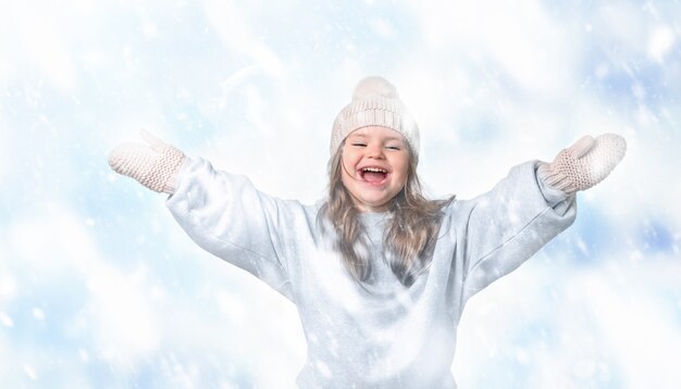 Menina criança feliz com chapéu e luvas pegando neve em uma caminhada