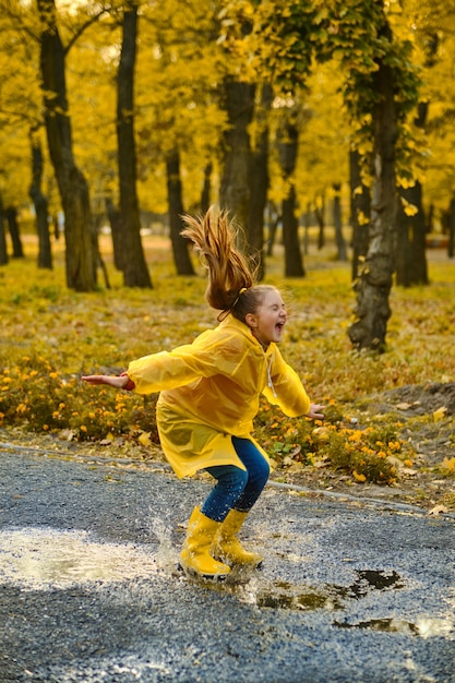 Menina criança feliz com guarda-chuva e botas de borracha