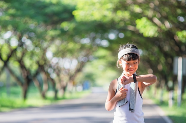 Menina criança feliz correndo no parque no verão na natureza. clarão de luz solar quente.