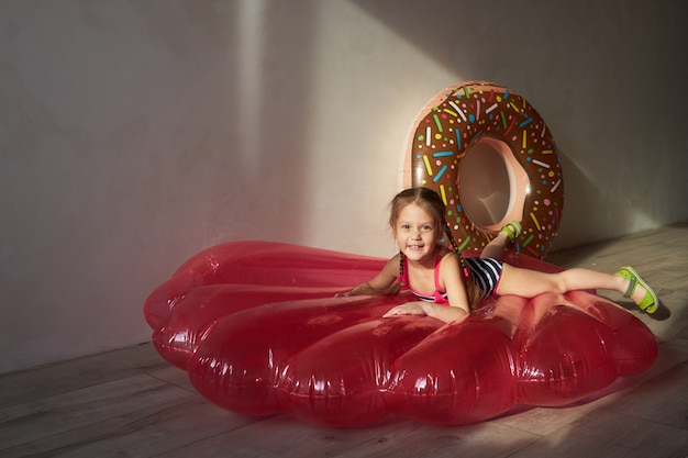 Menina criança feliz em um maiô e um chapéu de palha se prepara para uma viagem de verão em casa.