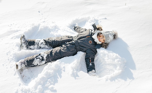 Menina criança feliz em uma caminhada de inverno com neve Vestindo um macacão de neve preto legal Roupa de inverno