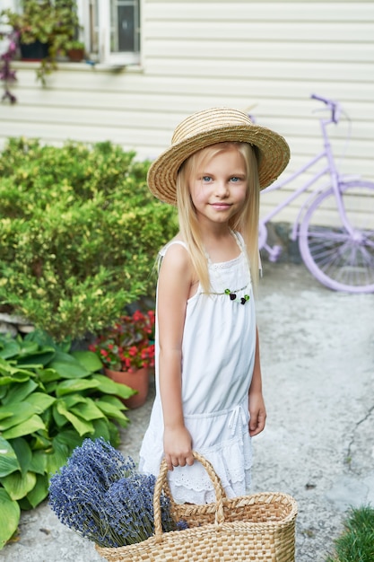 menina criança no chapéu com uma cesta de lavanda no jardim no verão