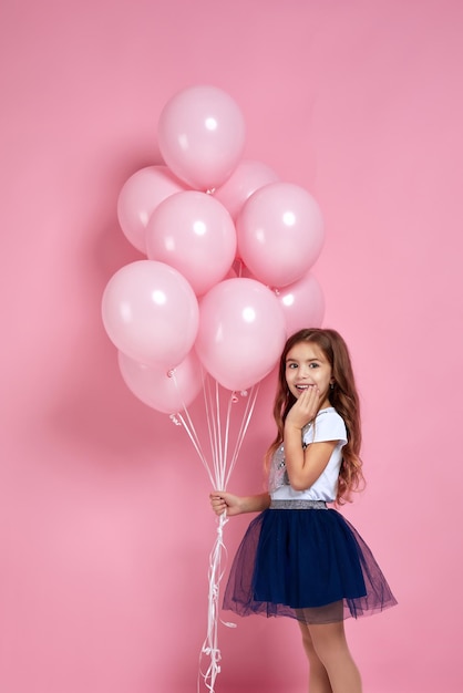Menina criança posando com balões de ar rosa pastel