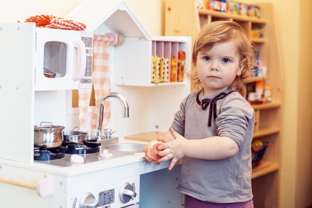 Menina criança, tocando, brinquedo, cozinha