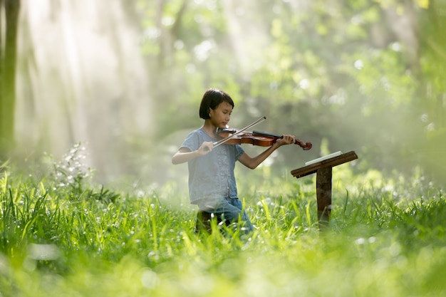 Menina criança tocando violino para estudar na tailândia