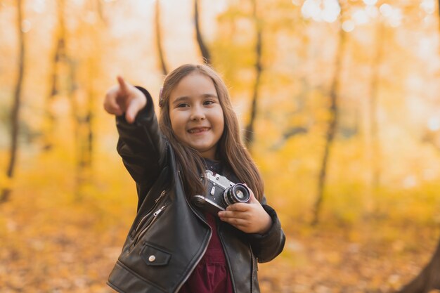 Menina criança usando uma câmera antiquada no outono fotógrafo de natureza outono e lazer