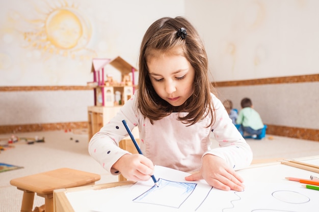 Menina criativa desenhando uma imagem com lápis azuis