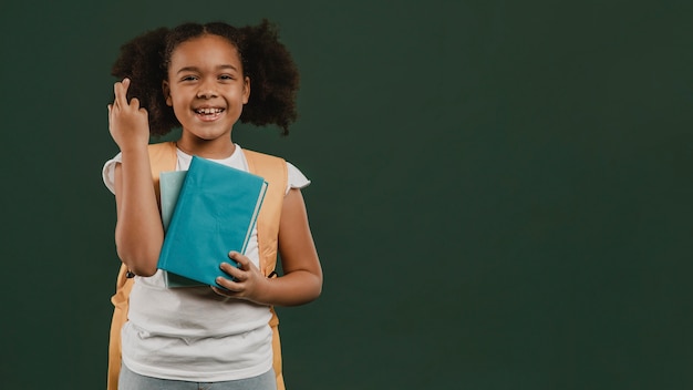 Foto menina cruzando os dedos e segurando o livro