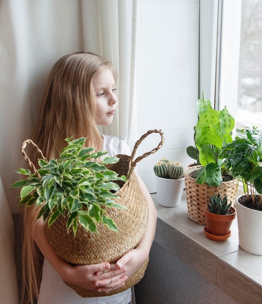 Menina cuidando das plantas da casa em casa