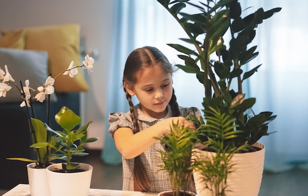 Menina cuidando de flores em vasos. As plantas da casa. Flores para casa. Menina regando flores no quarto