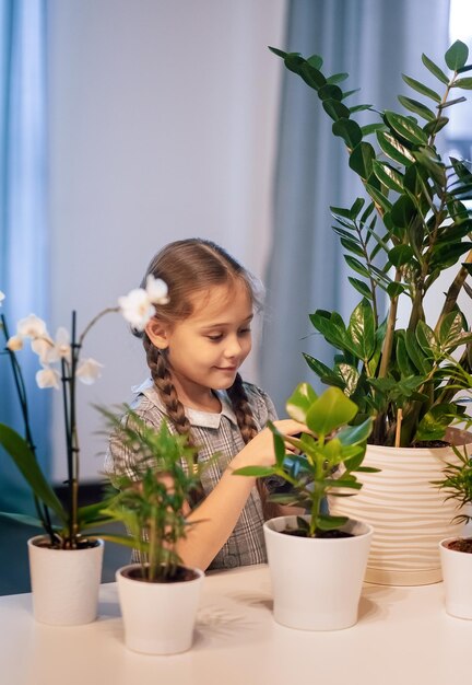 Menina cuidando de flores em vasos. As plantas da casa. Flores para casa. Menina regando flores no quarto