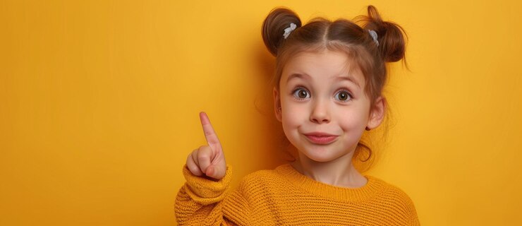 Foto menina curiosa apontando seu dedo indicador para algo em um fundo amarelo brilhante
