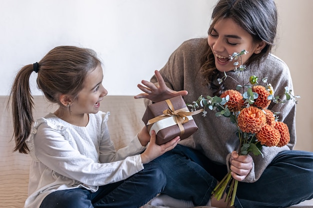 Menina dá à mãe uma caixa de presente e um buquê de flores de crisântemo, conceito de dia das mães, aniversário, dia da mulher.