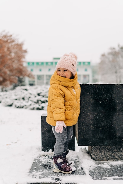 Menina da criança feliz com o dia de neve no inverno.