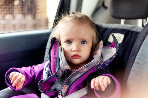 Menina da criança pequena sentada no banco do carro