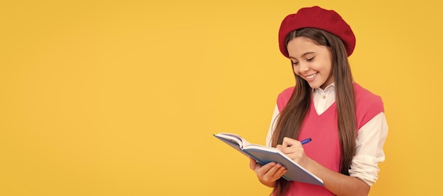 Menina da escola adolescente feliz na boina francesa fazendo anotações no bloco de notas do planejador ou no caderno Retrato