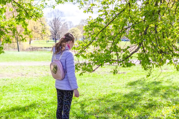 Menina da escola caminha no parque primavera