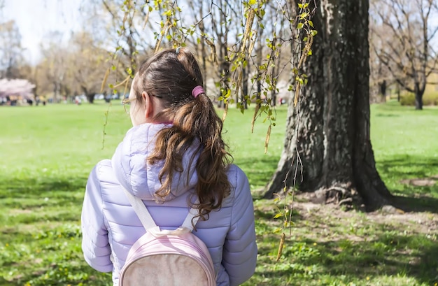 Menina da escola caminha no parque primavera