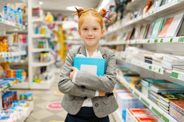 Menina da escola com cadernos em papelaria. Criança do sexo feminino comprando material de escritório na loja, estudante no supermercado