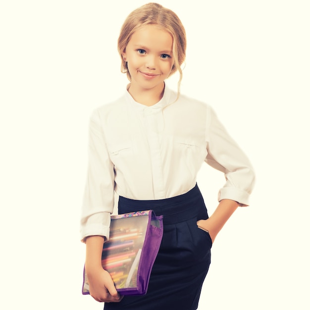 Menina da escola em branco. Criança de uniforme com material escolar, sorrindo para a câmera.