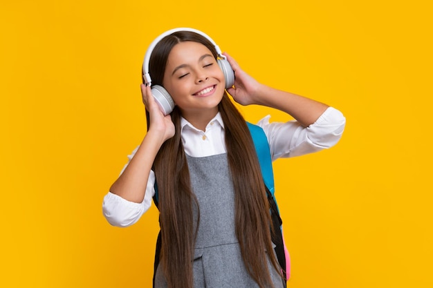 Menina da escola em fones de ouvido com mochila pronta para aprender Crianças em idade escolar com bolsa escolar isolada