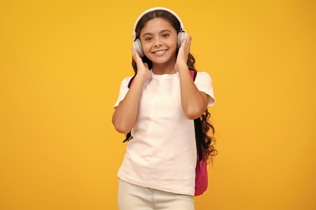 Menina da escola em fones de ouvido em fundo de estúdio isolado Conceito de escola e música