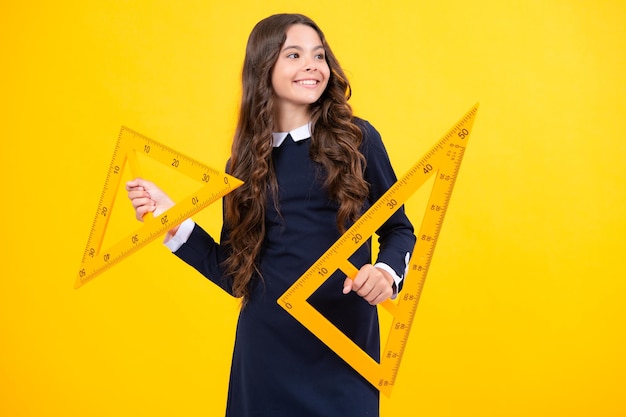 Menina da escola segurando medida para aula de geometria isolada em fundo amarelo Equipamento de medição Estudante estuda matemática