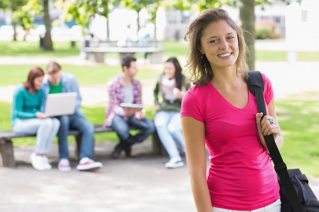 Menina da faculdade sorrindo com estudantes turva no parque