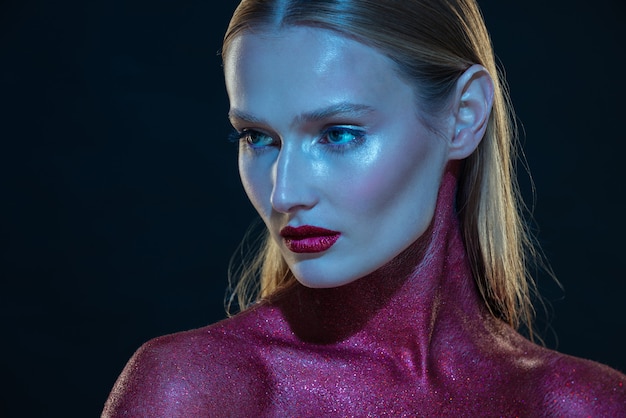 Menina da moda com pintura corporal vermelha em luz azul